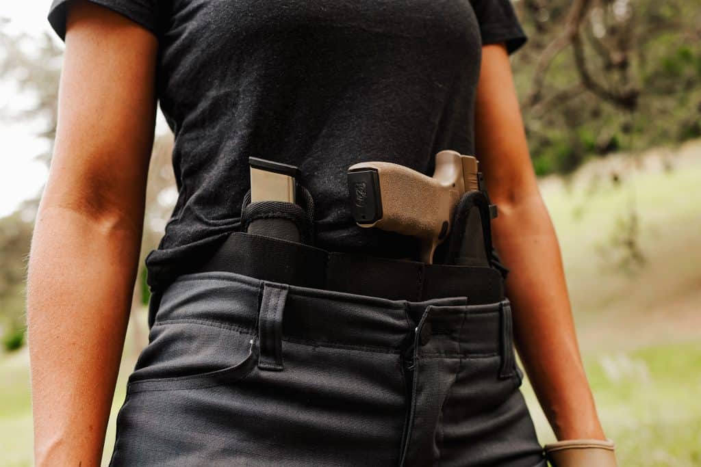A woman standing outdoors with a Sticky Holster and Mag Carrier